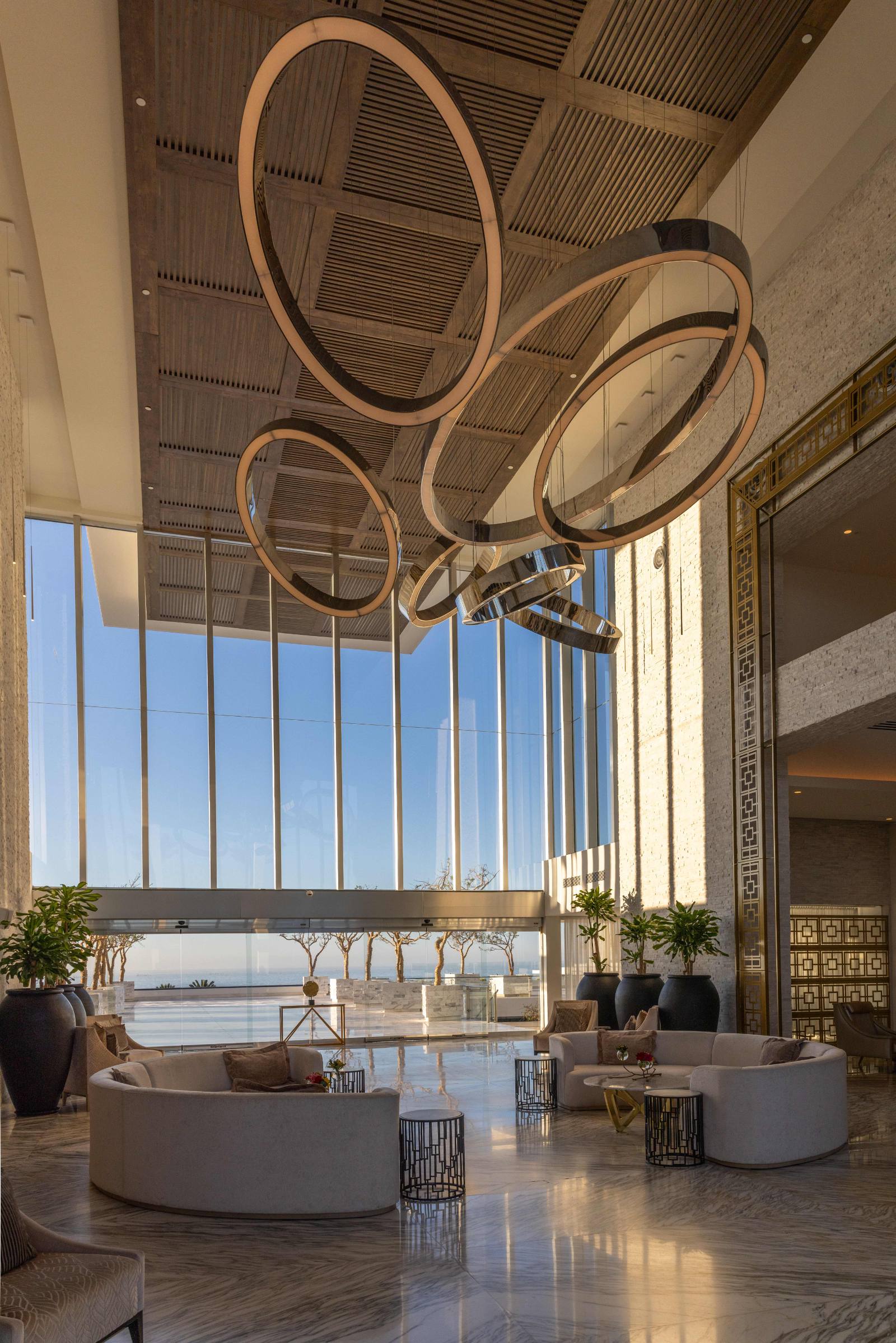 The lobby: double-height, ring chandeliers, and the water framed at the end