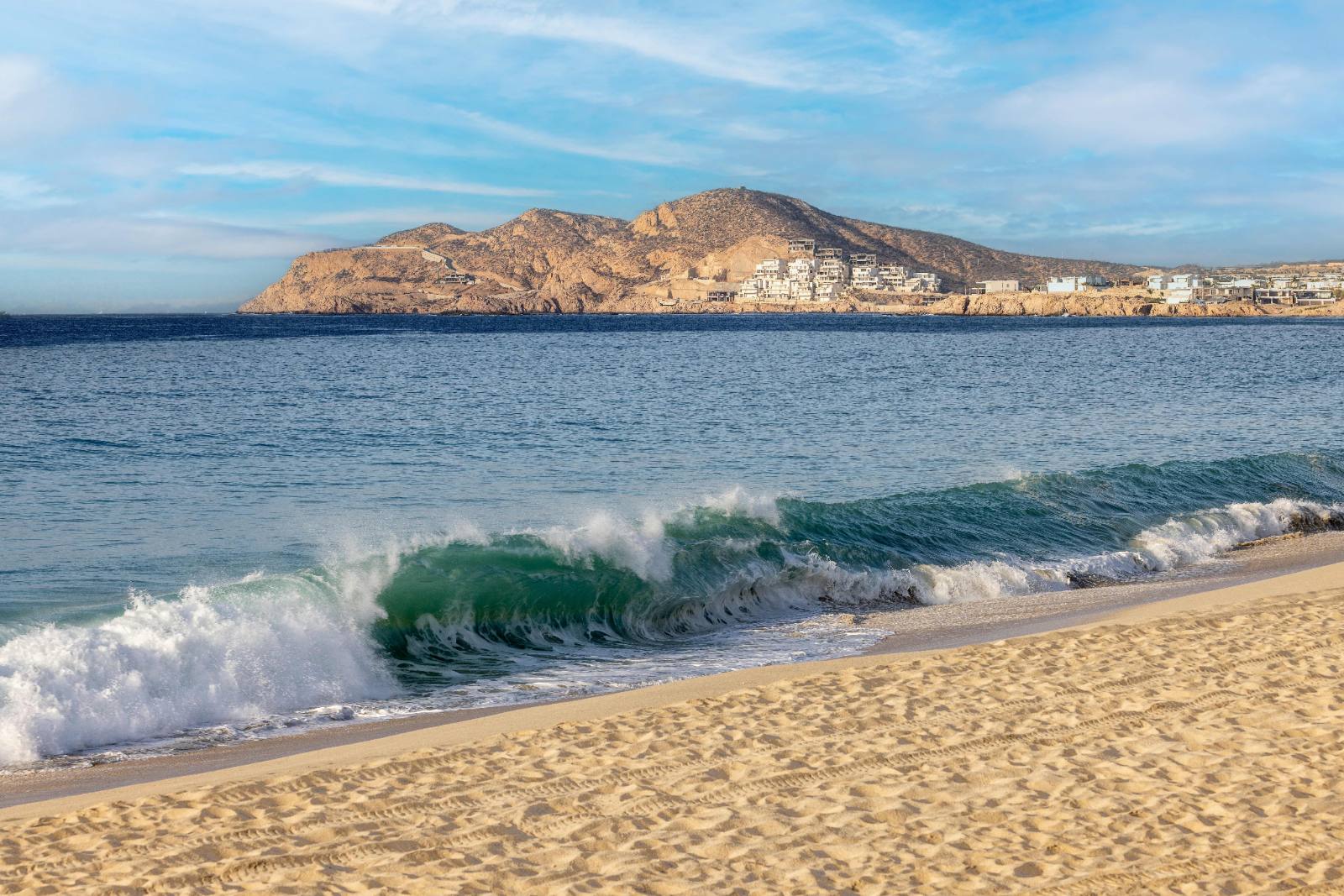 The beach in front of the property: real surf, and the Cabos headland across the bay