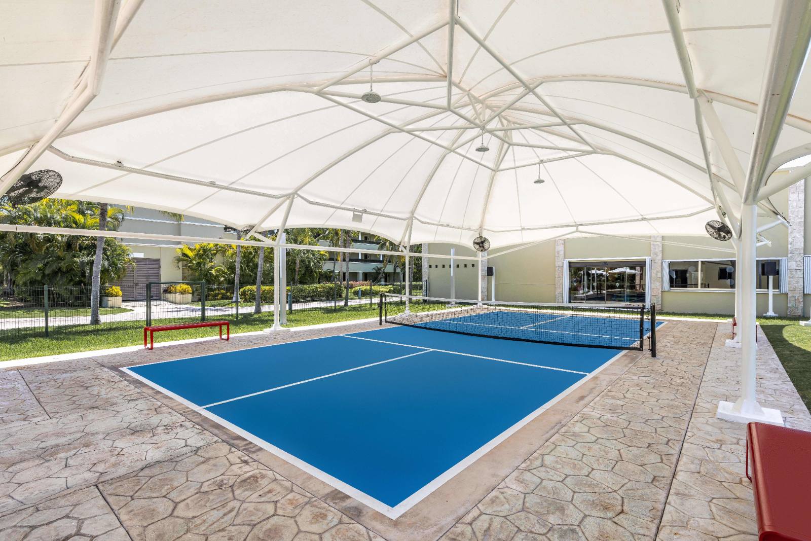 Pickleball under a shade canopy, with fans, so midday games are survivable