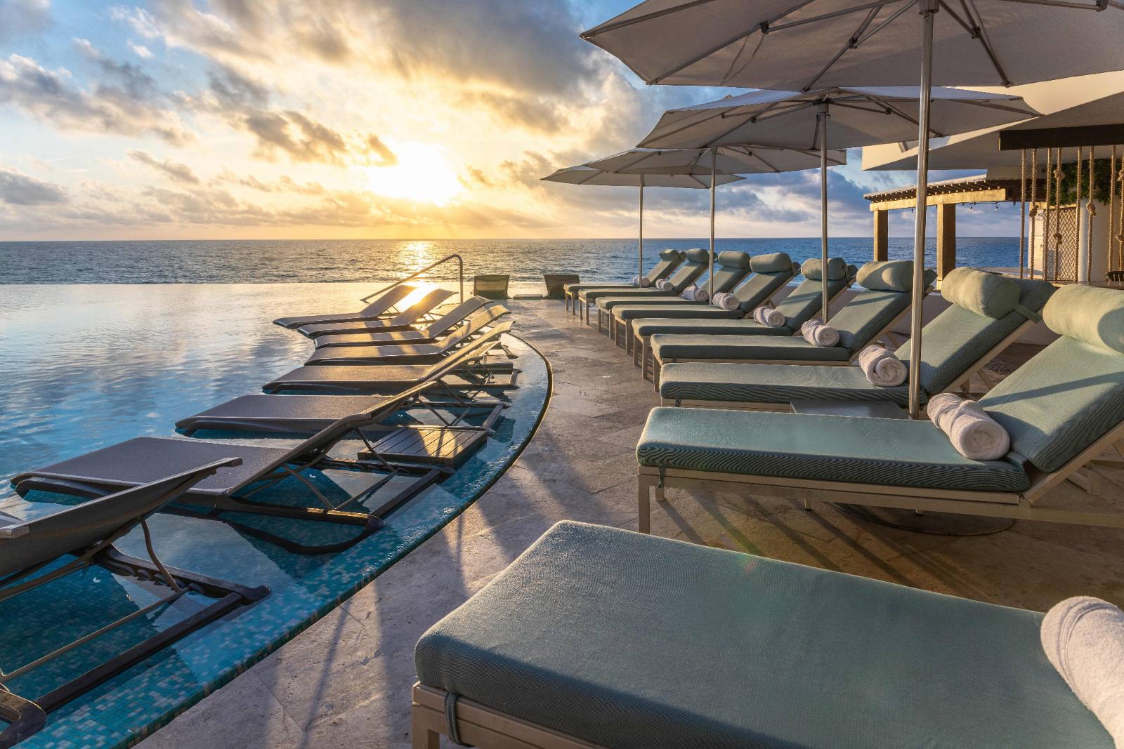 The main pool at sunrise: loungers in the water, ocean straight ahead