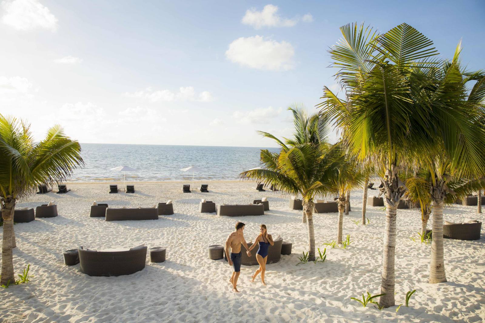 The beach club: daybeds set out on the sand, jungle behind, nothing built beyond